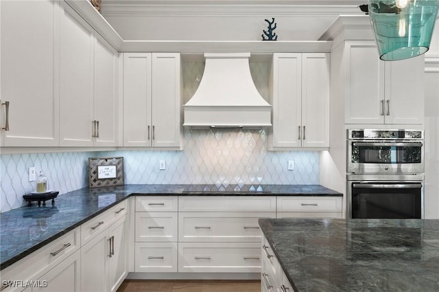 kitchen with premium range hood, double oven, white cabinetry, and black electric stovetop