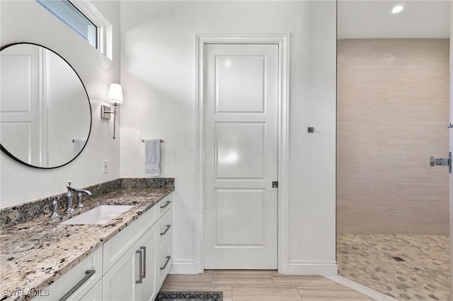 bathroom featuring recessed lighting, a tile shower, baseboards, and vanity