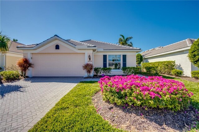 2626 Astwood Ct, Cape Coral, FL 33991 - ranch-style home with stucco siding, a tile roof, a garage, and decorative driveway