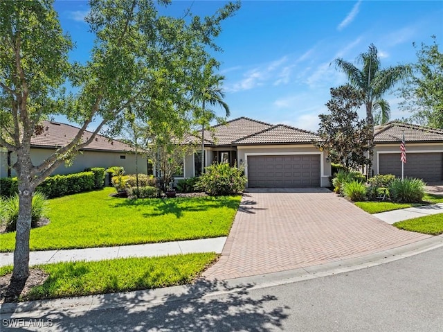 6068 Triumph Ln, Ave Maria, FL 34142 - view of front of property featuring an attached garage, stucco siding, a front lawn, a tiled roof, and decorative driveway