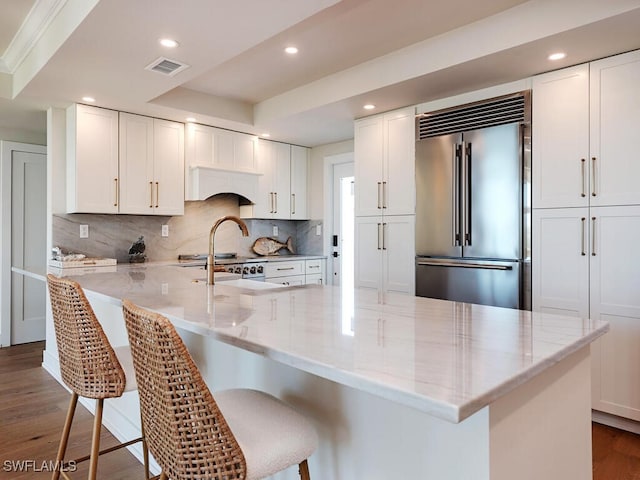 kitchen featuring white cabinets, dark wood-style floors, visible vents, and built in refrigerator