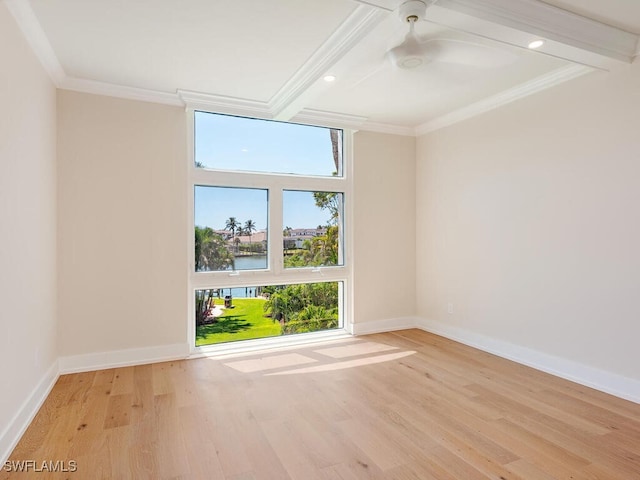 empty room with plenty of natural light, wood finished floors, baseboards, and ornamental molding