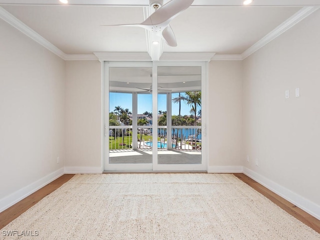 spare room featuring wood finished floors, crown molding, and a ceiling fan
