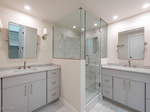 bathroom featuring a shower stall, two vanities, recessed lighting, and a sink