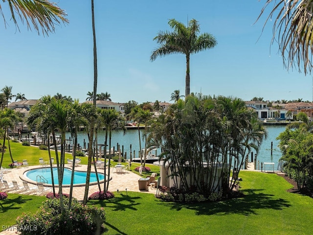 view of swimming pool with a water view and a lawn