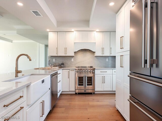 kitchen with white cabinets, high end appliances, and visible vents
