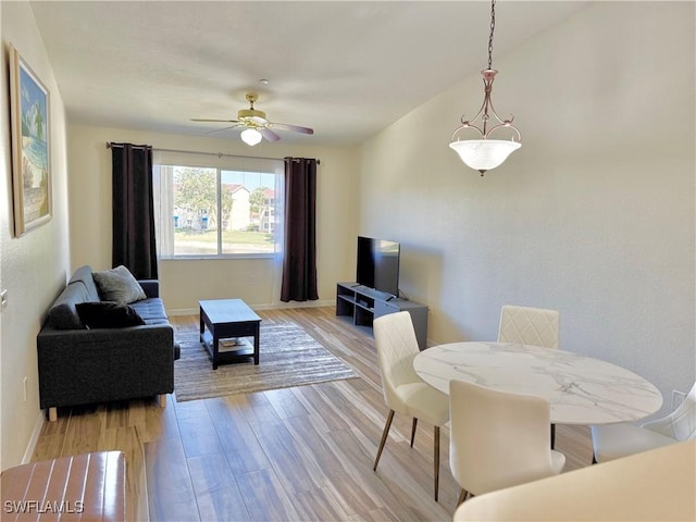 living room with light wood-type flooring, ceiling fan, and baseboards