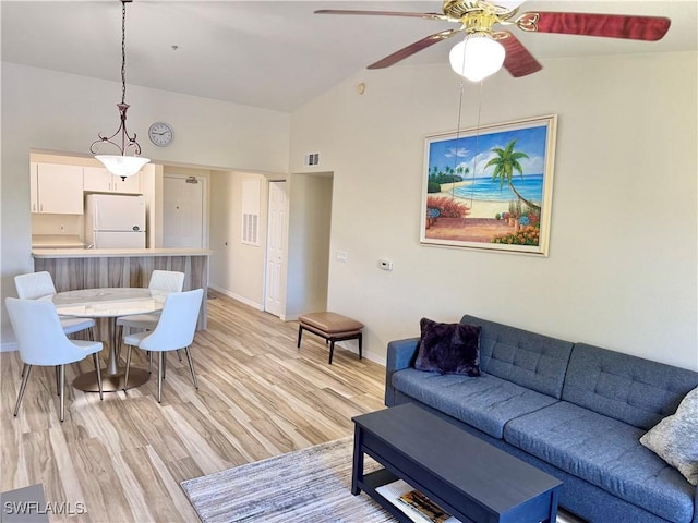 living room featuring high vaulted ceiling, light wood finished floors, baseboards, and ceiling fan