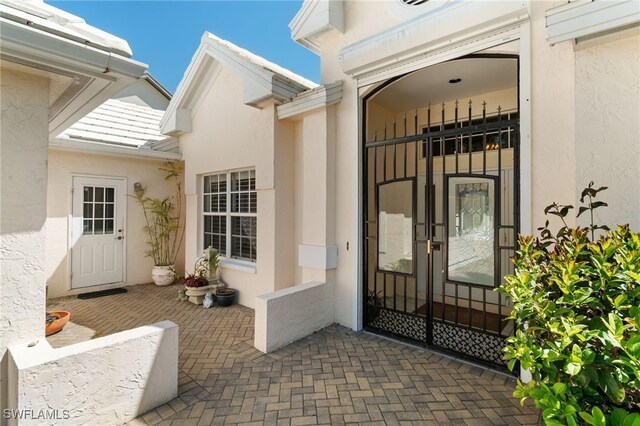 doorway to property featuring stucco siding and a patio
