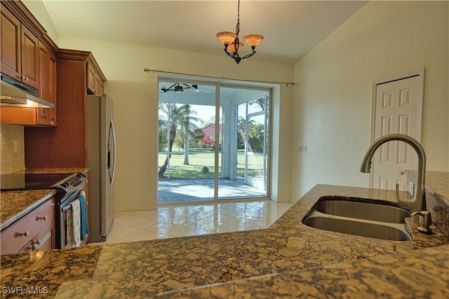 1675 Blue Lake Cir, Punta Gorda, FL 33983 - kitchen with dark stone countertops, brown cabinetry, a sink, stainless steel appliances, and tasteful backsplash