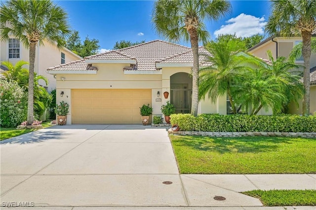 mediterranean / spanish home with a front lawn, stucco siding, a tile roof, driveway, and a garage