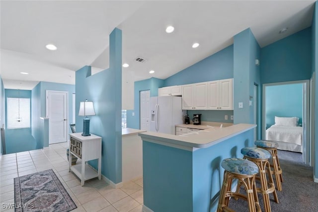 4970 Deerfield Way Unit F202, Naples, FL 34110 - kitchen featuring white refrigerator with ice dispenser, vaulted ceiling, light countertops, a breakfast bar, and white cabinetry