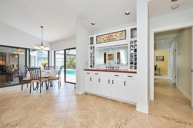 15440 Kilmarnock Dr, Fort Myers, FL 33912 - kitchen featuring white cabinets, an inviting chandelier, a sink, hanging light fixtures, and vaulted ceiling