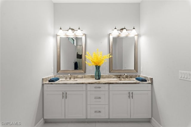 full bathroom featuring double vanity, baseboards, and a sink