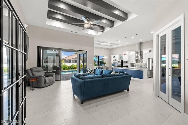 living area featuring marble finish floor, ceiling fan, french doors, and a raised ceiling