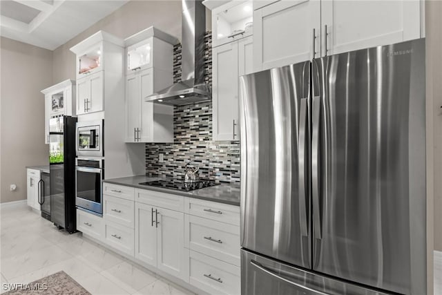 kitchen featuring marble finish floor, white cabinetry, tasteful backsplash, appliances with stainless steel finishes, and wall chimney range hood