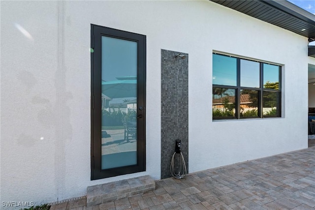 property entrance featuring stucco siding and a patio area
