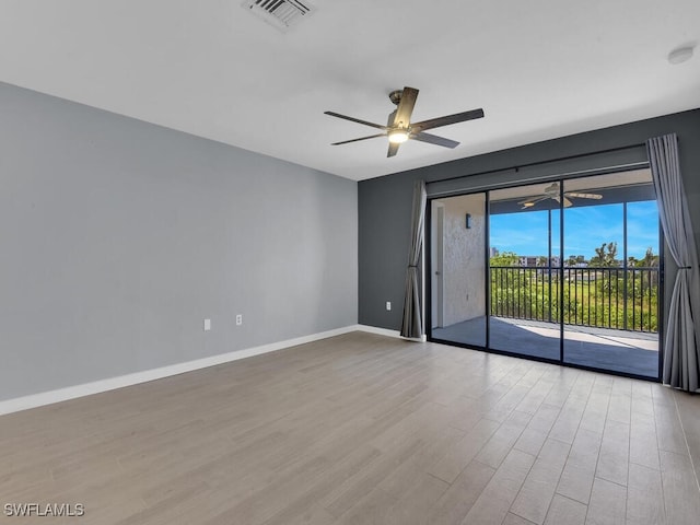 spare room with wood finished floors, ceiling fan, and baseboards