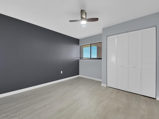 unfurnished bedroom with light wood-type flooring, baseboards, a closet, and ceiling fan