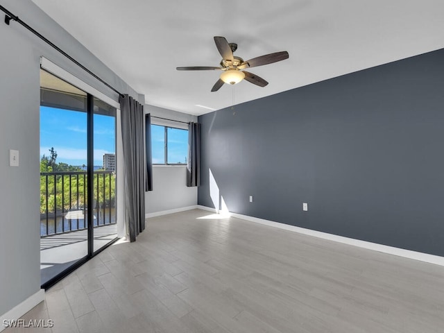 spare room with ceiling fan, wood finished floors, baseboards, and a water view