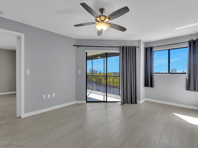 spare room with ceiling fan, wood finished floors, healthy amount of natural light, and baseboards