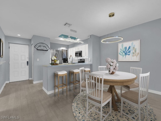 dining space featuring baseboards, wood finished floors, and recessed lighting