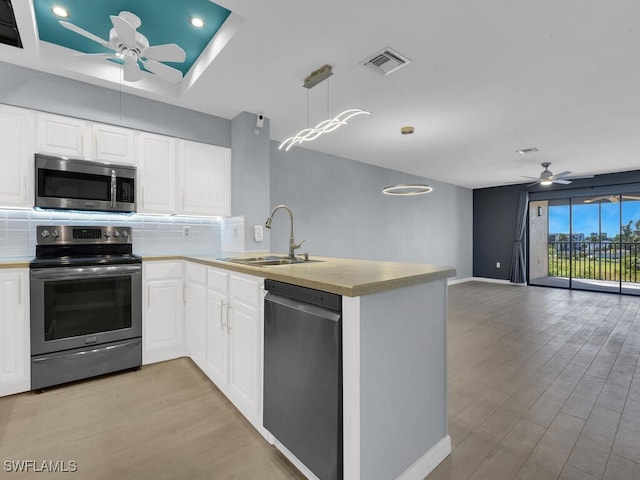 kitchen with stainless steel appliances, ceiling fan, a peninsula, a sink, and recessed lighting