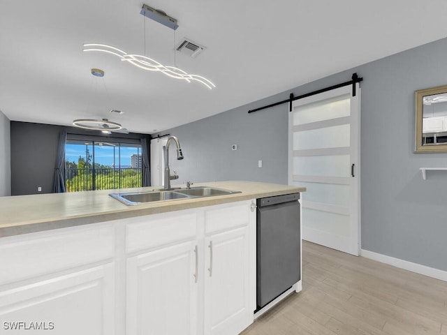 kitchen featuring a sink, dishwashing machine, a barn door, white cabinets, and light countertops