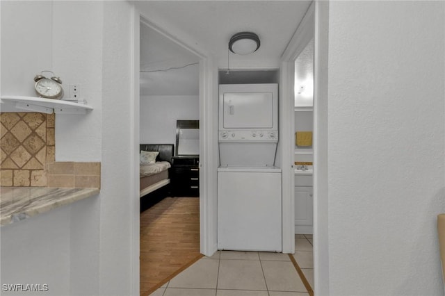 25100 Sandhill Blvd Unit 103, Punta Gorda, FL 33983 - bathroom featuring stacked washer and clothes dryer, decorative backsplash, and tile patterned floors
