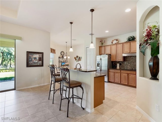 21826 Bella Terra Blvd, Estero, FL 33928 - kitchen featuring a wealth of natural light, backsplash, stainless steel fridge with ice dispenser, a breakfast bar, and dark countertops