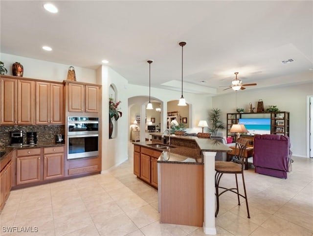 21826 Bella Terra Blvd, Estero, FL 33928 - kitchen featuring open floor plan, a kitchen bar, double oven, a sink, and arched walkways