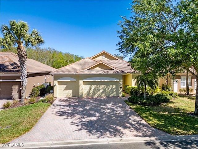 21826 Bella Terra Blvd, Estero, FL 33928 - mediterranean / spanish-style house featuring stucco siding, a tile roof, a garage, and decorative driveway