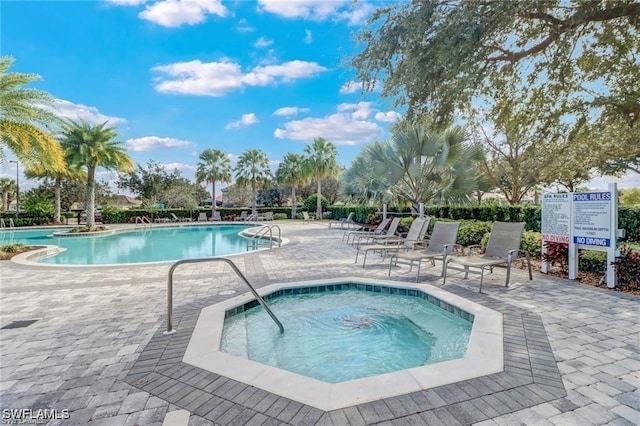 pool featuring a hot tub and a patio area