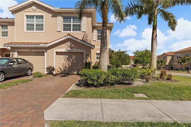 view of front of house with a tile roof, an attached garage, stucco siding, and driveway