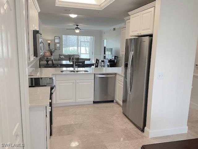 kitchen featuring open floor plan, light countertops, stainless steel appliances, a sink, and white cabinets
