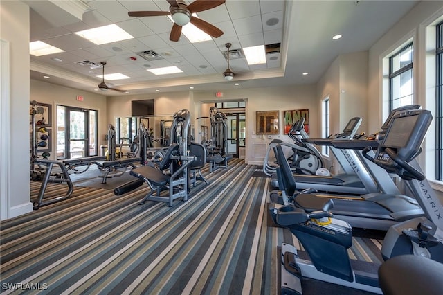 gym with a ceiling fan, visible vents, carpet floors, baseboards, and a tray ceiling