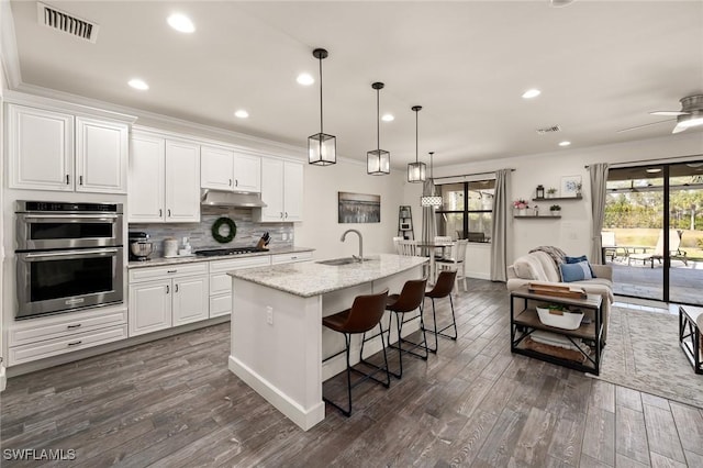 kitchen featuring visible vents, ornamental molding, under cabinet range hood, a sink, and double oven