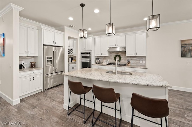 kitchen with dark wood-type flooring, baseboards, under cabinet range hood, ornamental molding, and appliances with stainless steel finishes