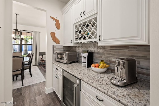 kitchen featuring light stone counters, dark wood finished floors, a toaster, wine cooler, and white cabinets