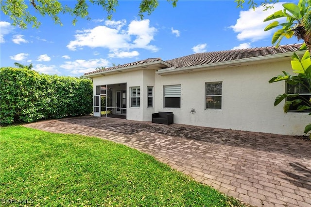 2160 Vardin Pl, Naples, FL 34120 - back of house with a sunroom, a lawn, a patio area, stucco siding, and a tiled roof