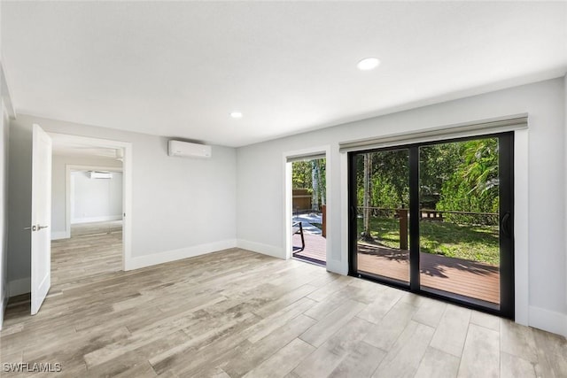 unfurnished room with baseboards, recessed lighting, light wood-style floors, and a wall mounted air conditioner