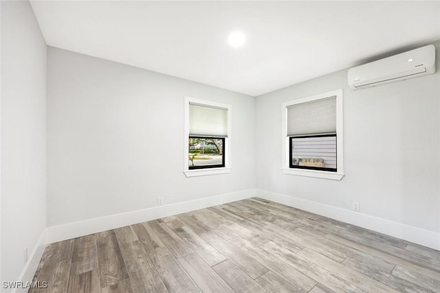 empty room featuring an AC wall unit, baseboards, and wood finished floors