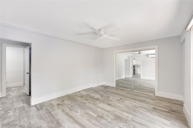 spare room with a wall unit AC, baseboards, a ceiling fan, and wood finished floors