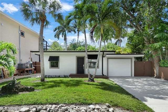 view of front of home featuring stucco siding, fence, a front lawn, a garage, and concrete driveway