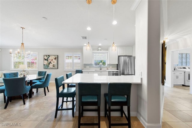 28970 Vermillion Ln, Bonita Springs, FL 34135 - kitchen featuring appliances with stainless steel finishes, decorative backsplash, light countertops, a kitchen bar, and white cabinets