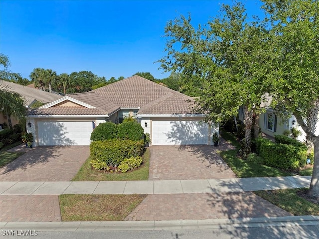 28970 Vermillion Ln, Bonita Springs, FL 34135 - view of front of house with an attached garage, decorative driveway, a tiled roof, and stucco siding
