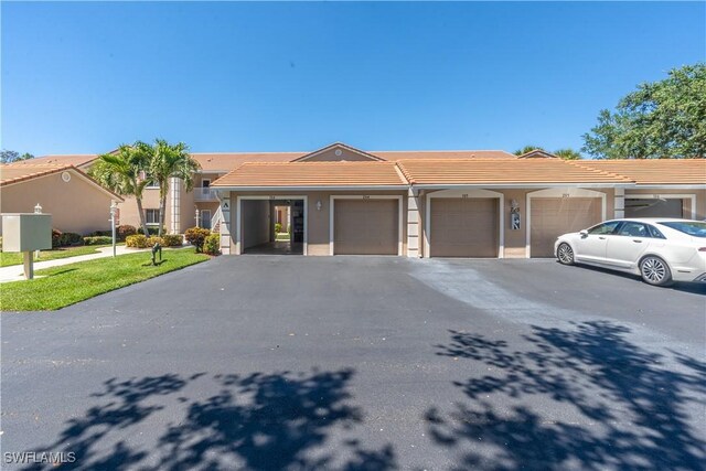 ranch-style home featuring stucco siding, community garages, and a tiled roof