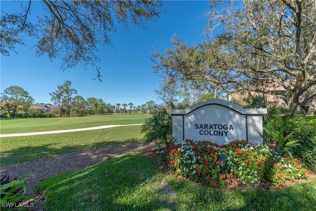 community sign featuring a lawn and view of golf course