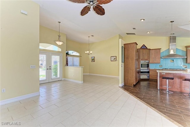 1368 Grebe Dr, Punta Gorda, FL 33950 - kitchen featuring open floor plan, a breakfast bar, french doors, exhaust hood, and brown cabinetry