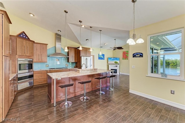 1368 Grebe Dr, Punta Gorda, FL 33950 - kitchen featuring oven, a warming drawer, brown cabinets, wall chimney range hood, and ceiling fan